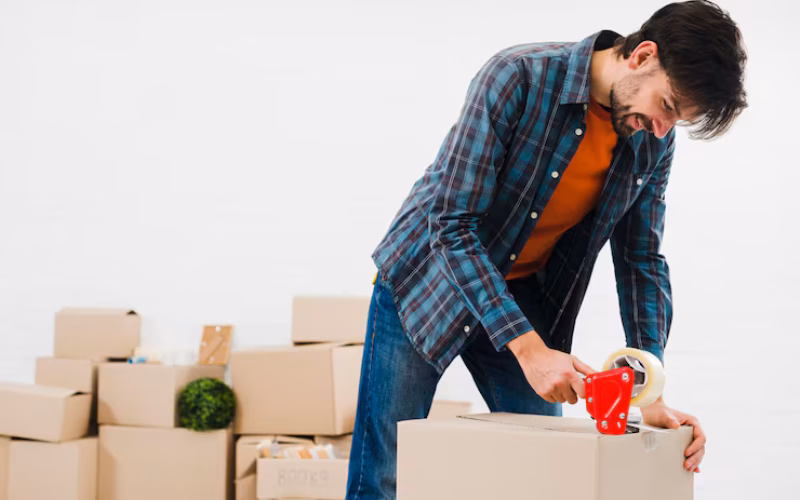 Smiling Portrait Young Man Sealing Cardboard Box With Duct Tape 23 2148095497 - Envoymovers