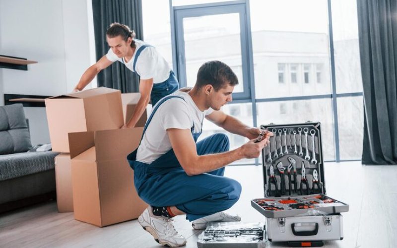 Uses Tools From Case Two Young Movers Blue Uniform Working Indoors Room 146671 52009 - Envoymovers